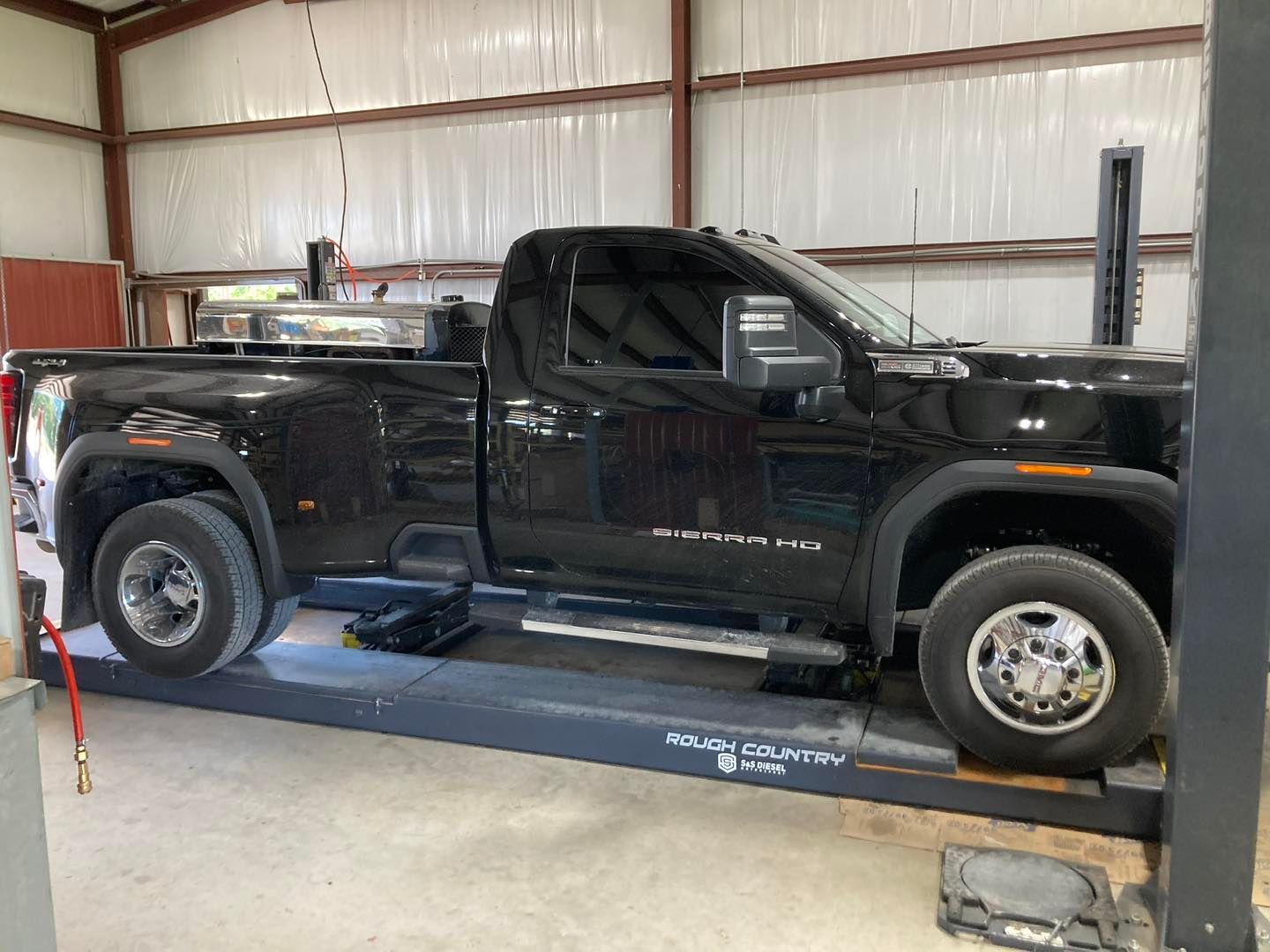 Black pickup truck on a vehicle lift inside a garage workshop.