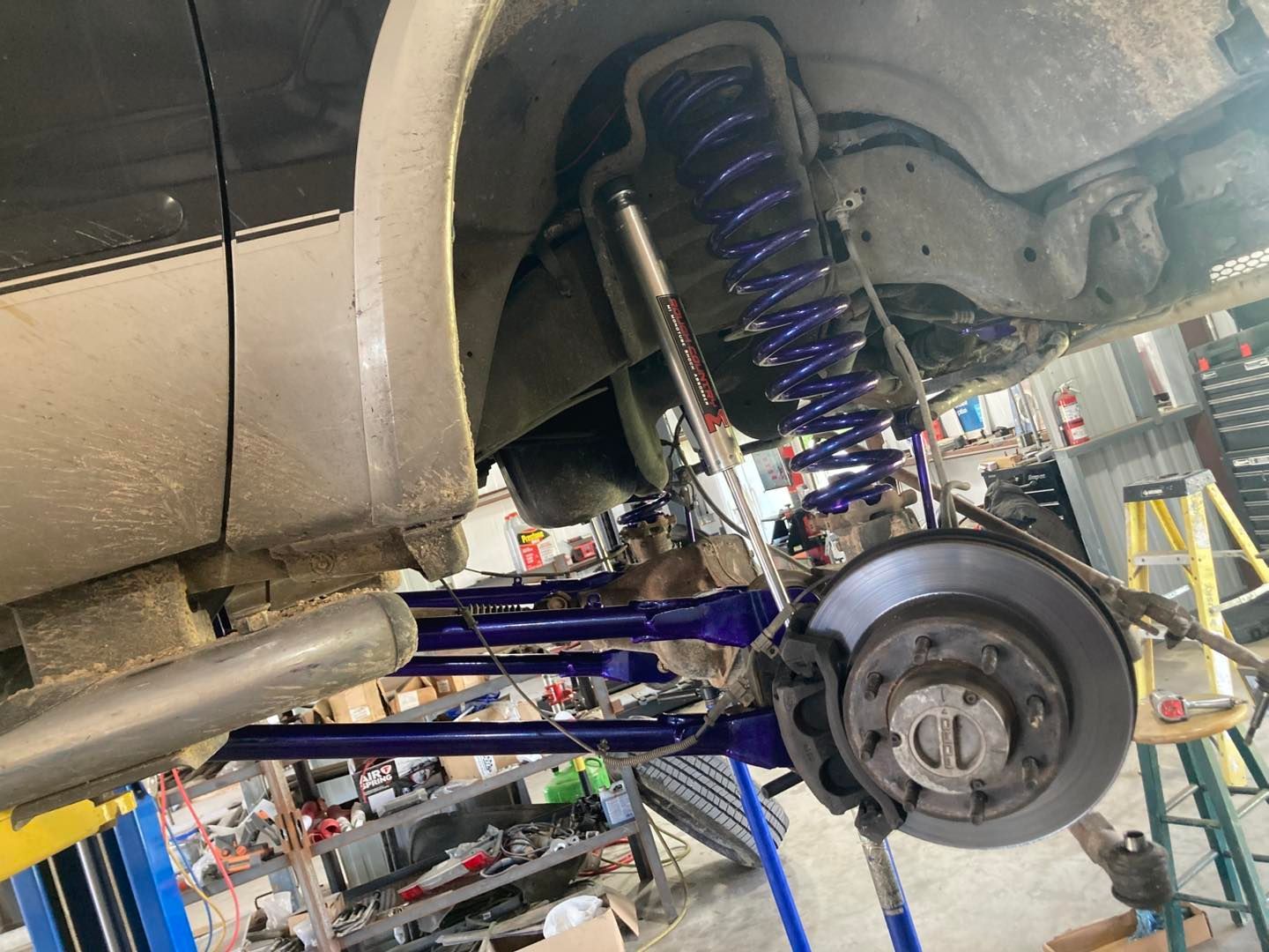 Car wheel and suspension assembly under a raised vehicle in a repair shop