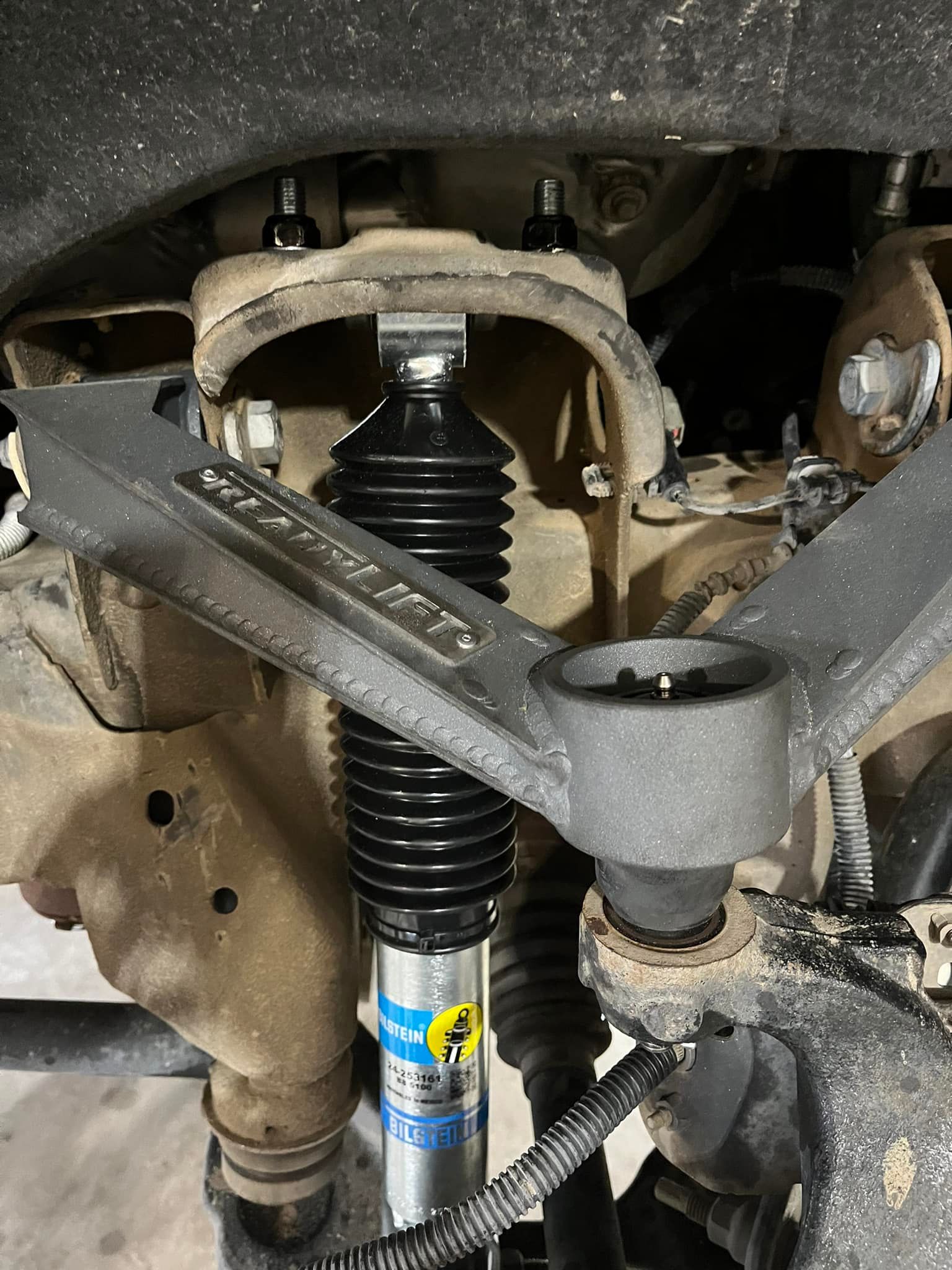 Car suspension with a vertical strut and control arms under a dusty wheel well