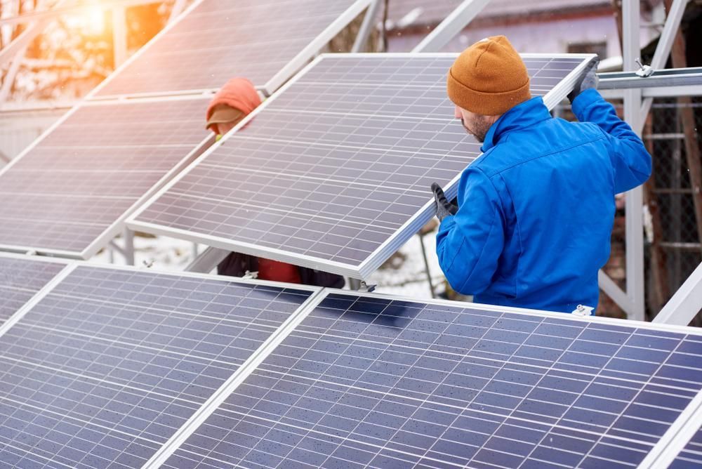 Two Men Are Installing Solar Panels On A Roof — Mission Solar And Electrical In Mission Beach, QLD