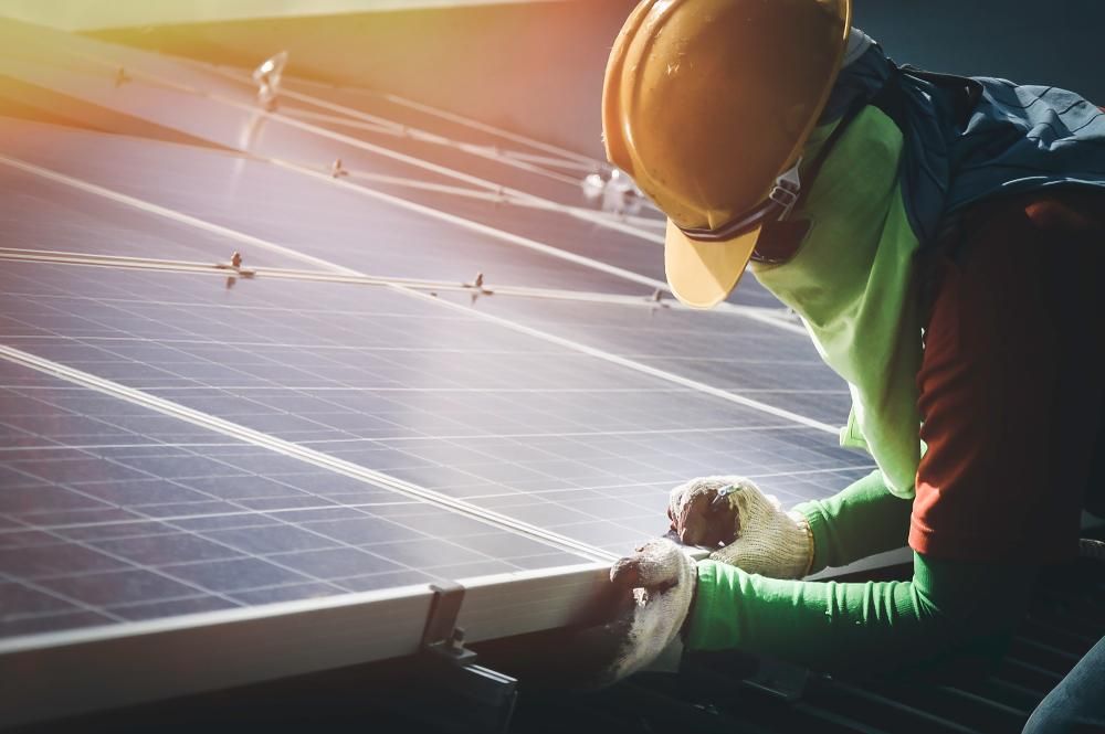 A Man Is Working On A Solar Panel On A Roof — Mission Solar And Electrical In Cardwell, QLD