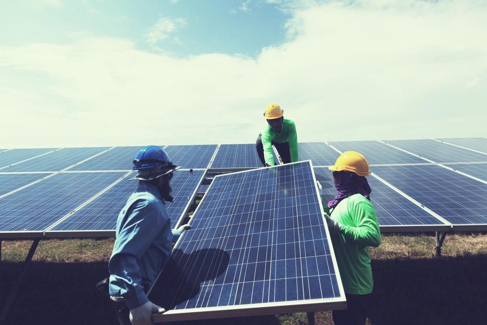 A Group Of People Are Installing Solar Panels On A Roof — Mission Solar And Electrical In Mission Beach, QLD