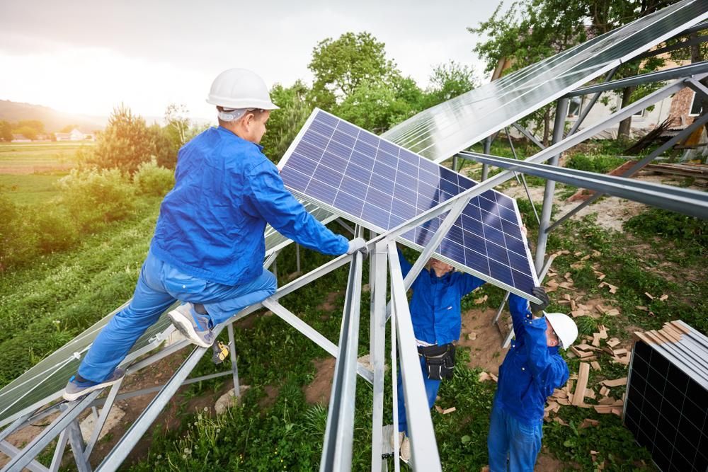 A Group Of Men Are Installing Solar Panels On A Roof — Mission Solar And Electrical In Cardwell, QLD
