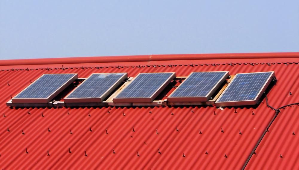 A Red Roof With Four Solar Panels On It — Mission Solar And Electrical In Tully, QLD
