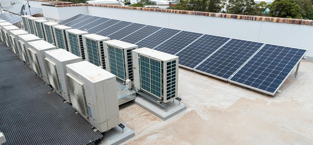 A Row Of Air Conditioners And Solar Panels On The Roof Of A Building — Mission Solar And Electrical In Cardwell, QLD