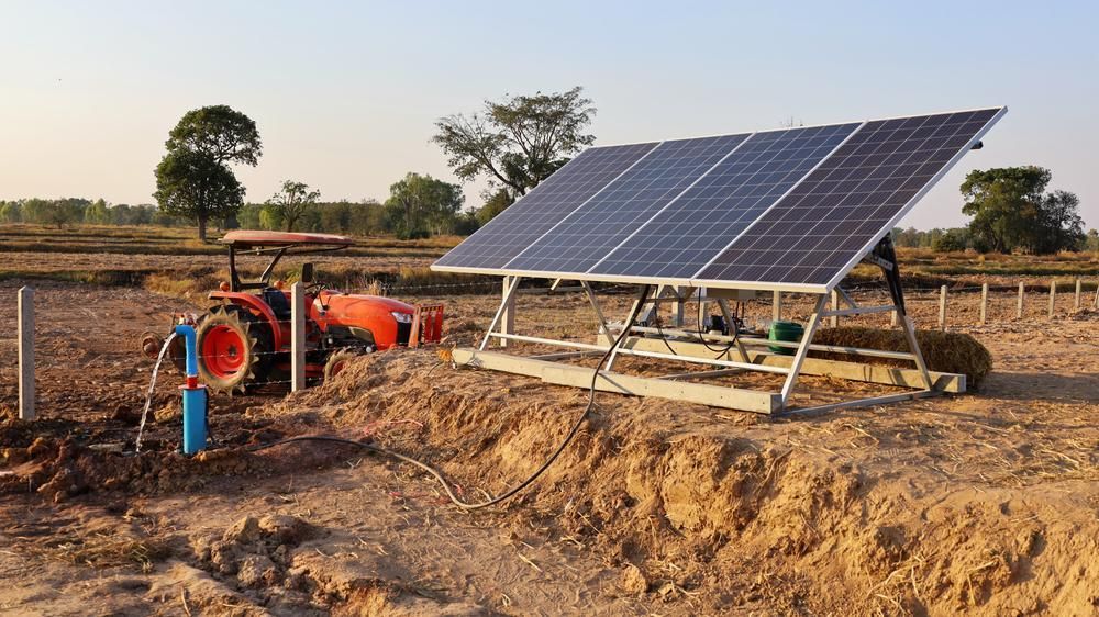 A Solar Panel Is Sitting On Top Of A Dirt Field Next To A Tractor — Mission Solar And Electrical In Innisfail, QLD