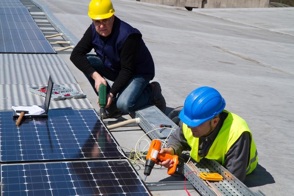 Two Men Are Installing Solar Panels On A Roof — Mission Solar And Electrical In Tully, QLD