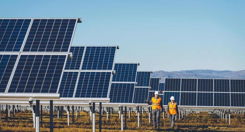 Two Men Are Standing In Front Of A Row Of Solar Panels — Mission Solar And Electrical In Cardwell, QLD