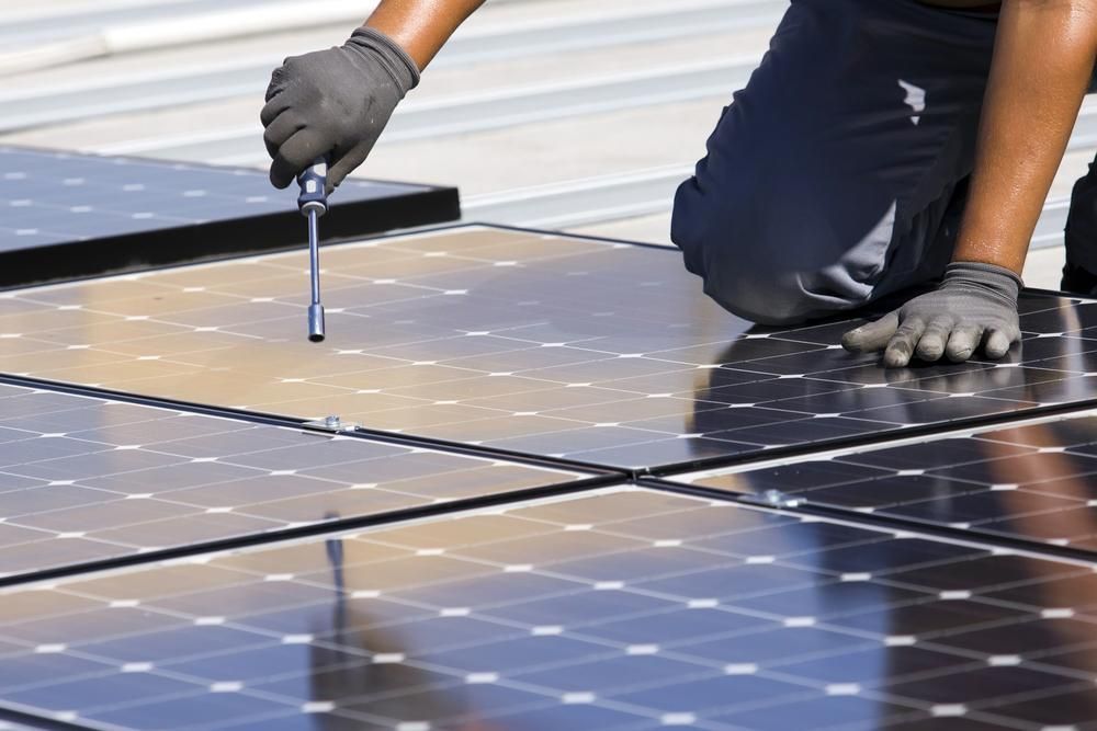 A Man Is Working On A Solar Panel With A Screwdriver — Mission Solar And Electrical In Mission Beach, QLD