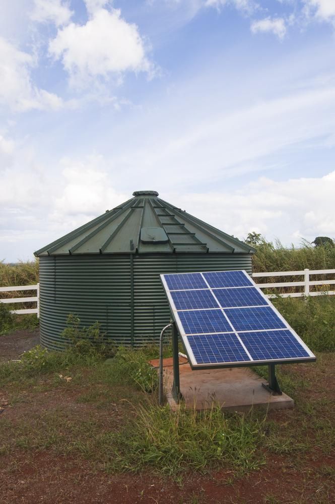 A Solar Panel Is Sitting In Front Of A Water Tank — Mission Solar And Electrical In Tully, QLD