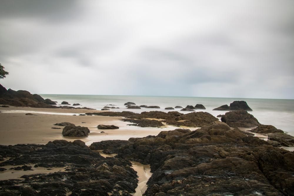 A Rocky Beach With A Cloudy Sky In The Background — Mission Solar And Electrical In Innisfail, QLD