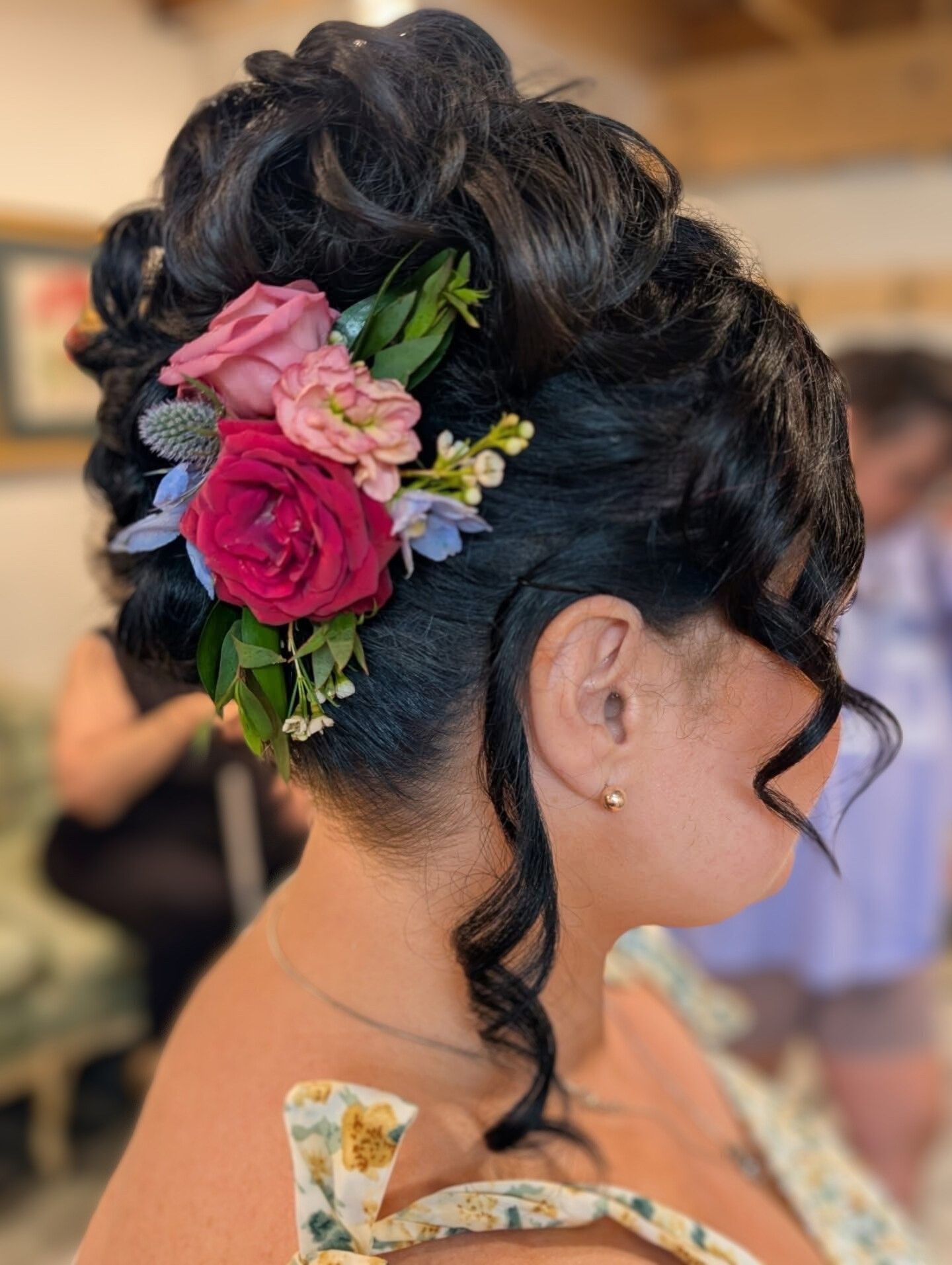 Woman with updo hairstyle adorned with flowers, in a well-lit indoor setting.
