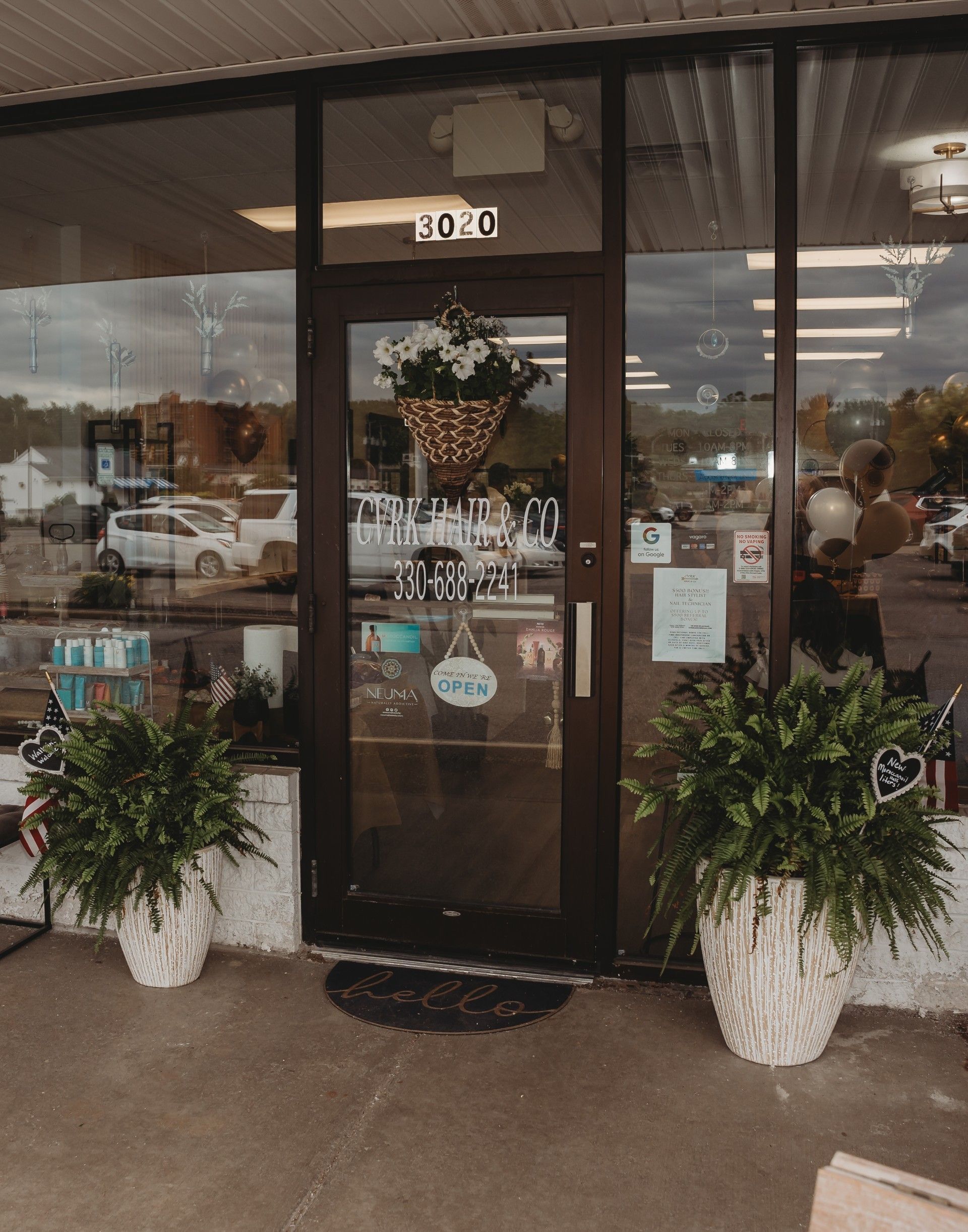 Storefront with glass door, floral basket, ferns, and shop sign.
