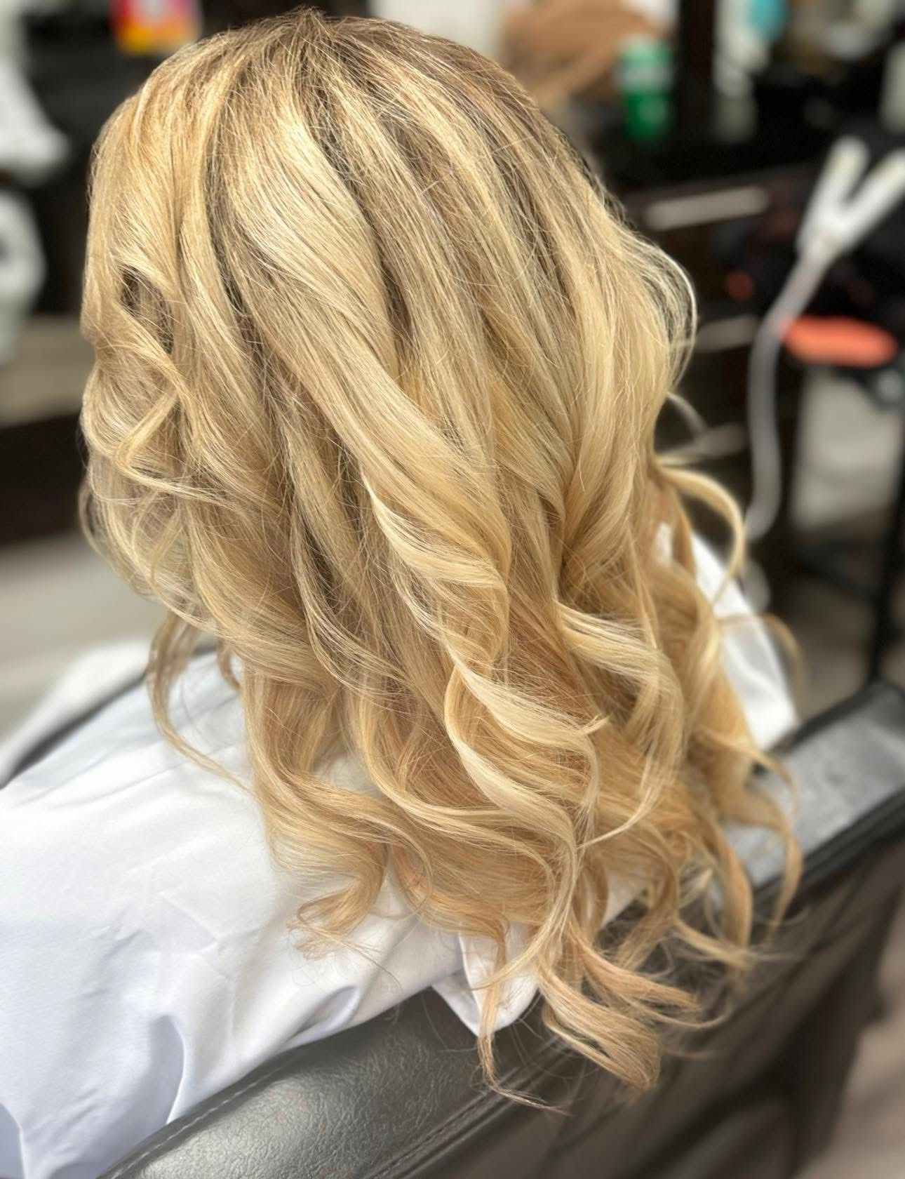 Blonde hair styled in loose curls in a salon setting.