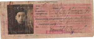 A vintage document with a portrait of a person, likely an identification card. Pink-tinted paper, faded ink, and handwriting.