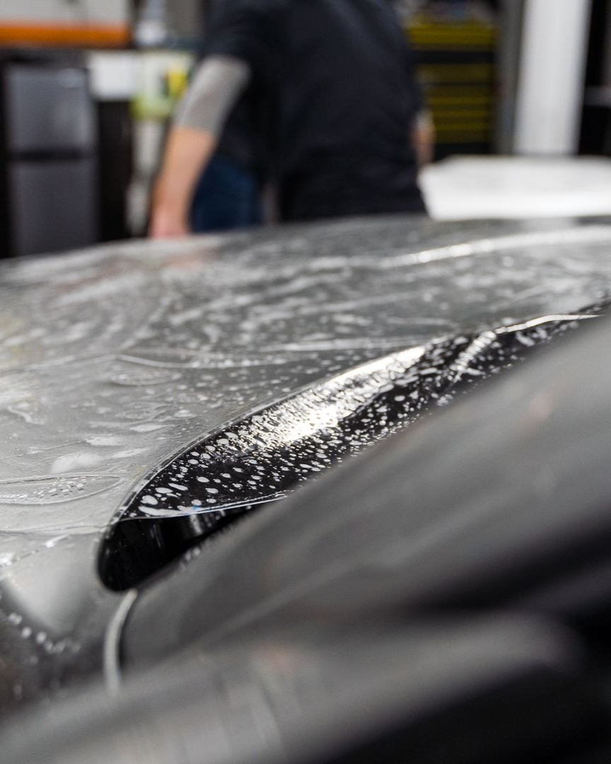 A car is covered in plastic wrap in a garage.