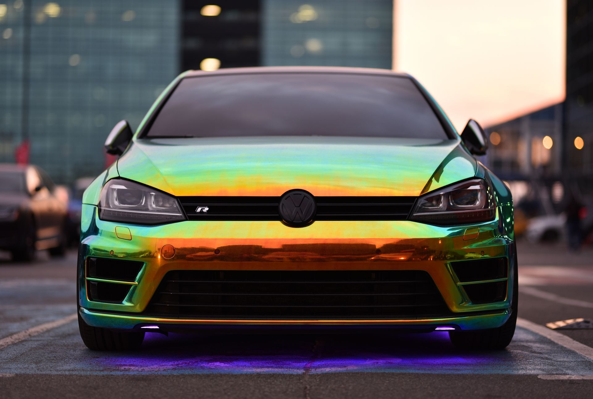 Volkswagen Golf R with iridescent wrap parked, glowing purple ground lights.