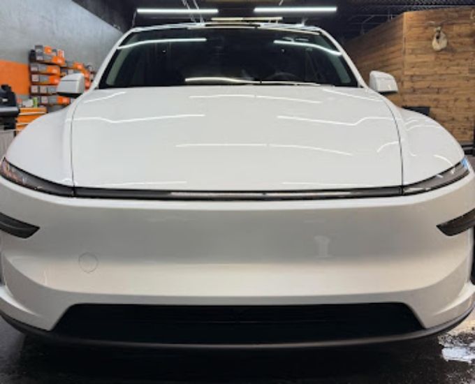 White electric SUV front view inside shop showing a clean ceramic coating finish