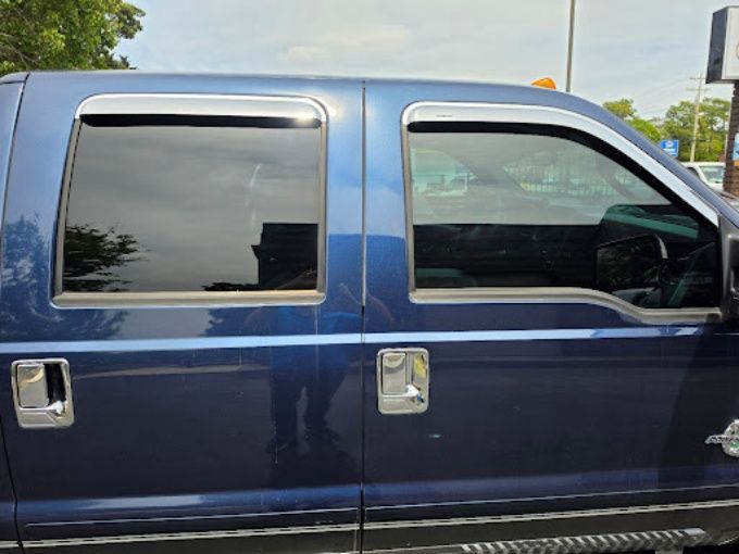 Blue Ford Econoline van with dark window tint applied across all side windows