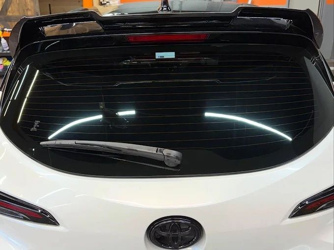 White Toyota rear windshield with a smooth dark window tint and factory spoiler