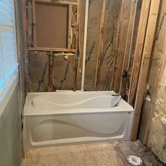 A bathtub is sitting in a bathroom under construction.