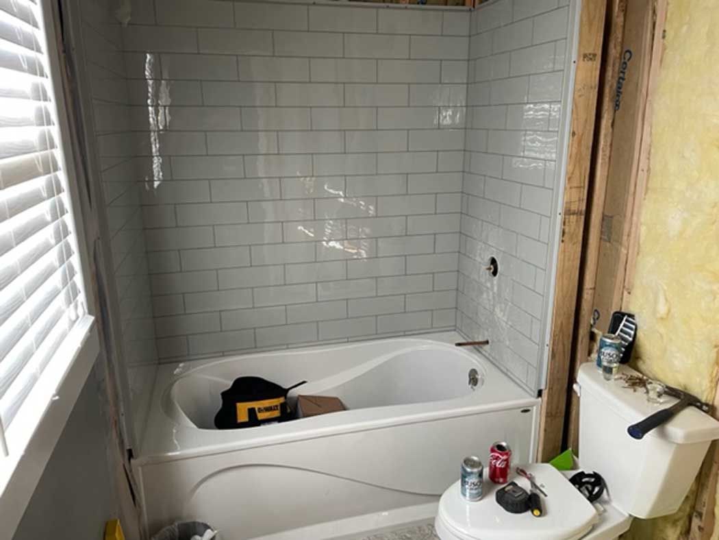 A bathroom with a tub , toilet , and window.