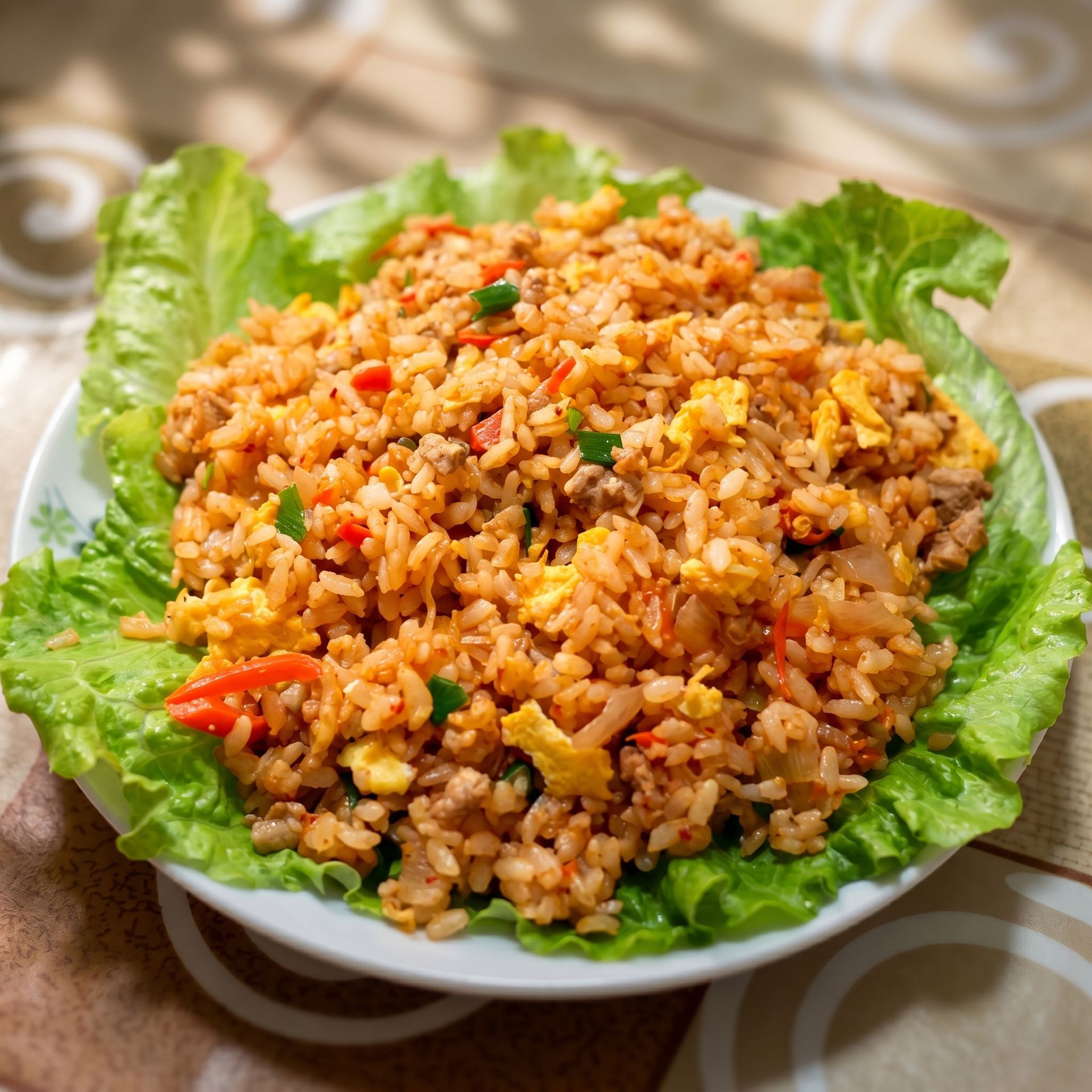 Plate of fried rice garnished with lettuce leaves, with red and green vegetables visible