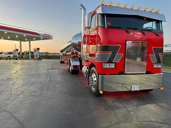 A red semi truck is parked in front of a gas station.