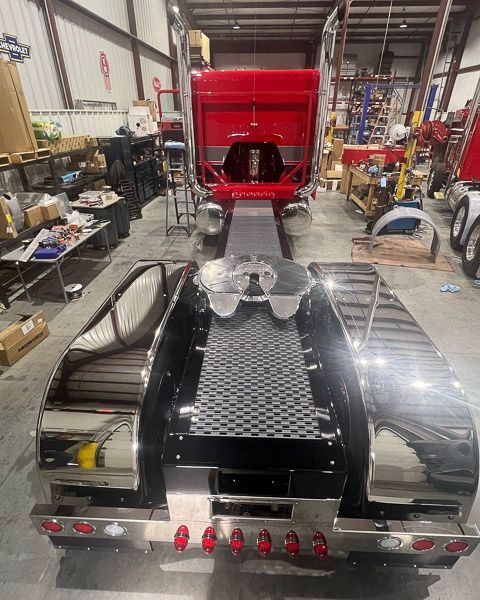 A red semi truck is being built in a garage.