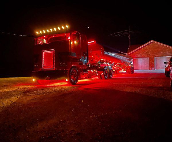A red truck is parked in a driveway at night.