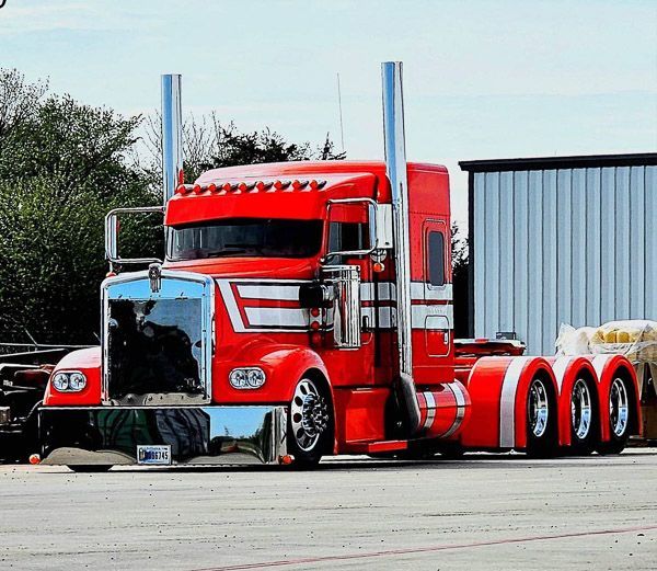 A red semi truck is parked in front of a building.