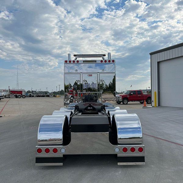 A silver semi truck is parked in a parking lot