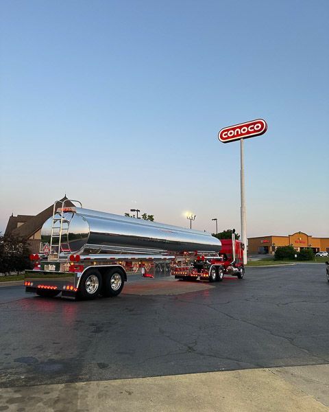 A tanker truck is parked in front of a conco sign