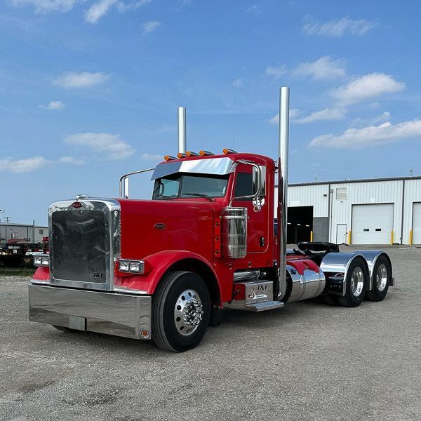 A red semi truck is parked in a parking lot