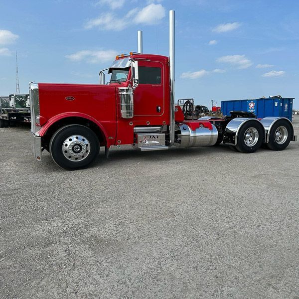 A red semi truck is parked in a parking lot