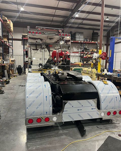 A semi truck is being worked on in a garage.