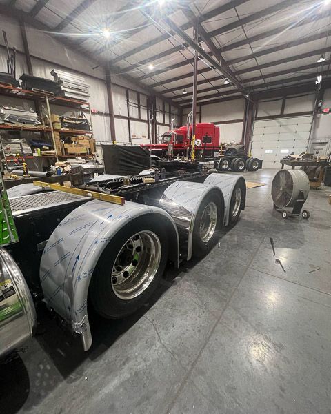 A row of semi trucks are parked in a warehouse.