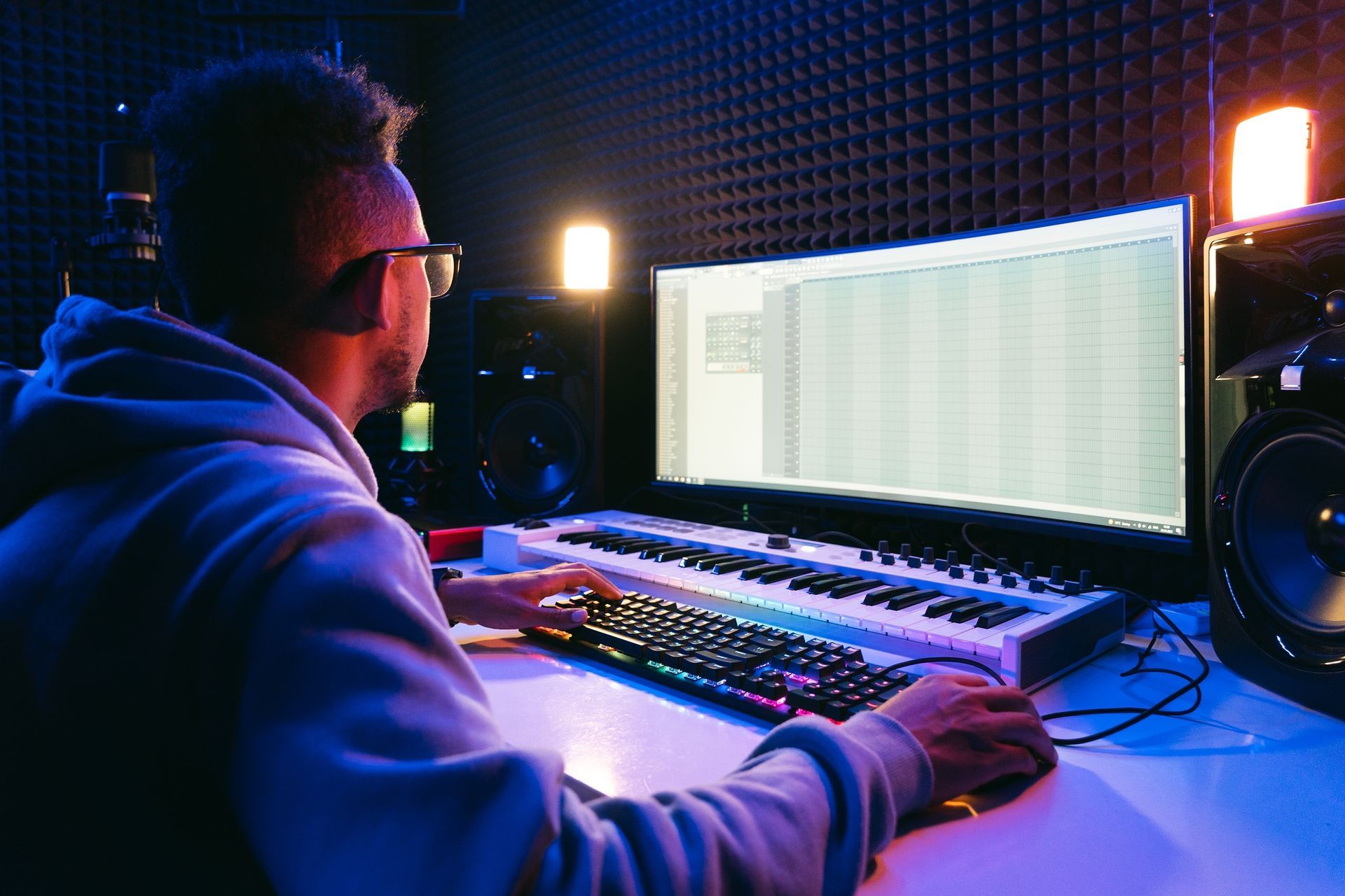 A man is sitting in front of a computer in a recording studio.