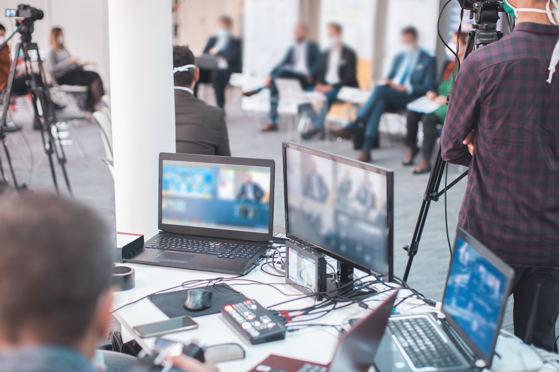 A man is standing in front of a table with laptops and monitors.
