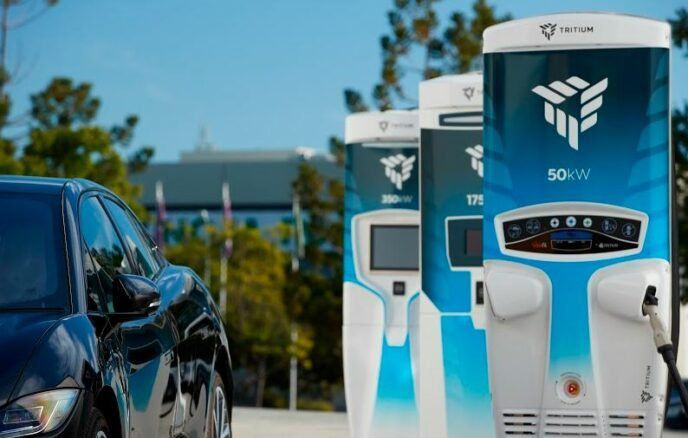 A black electric car is being charged at a charging station.