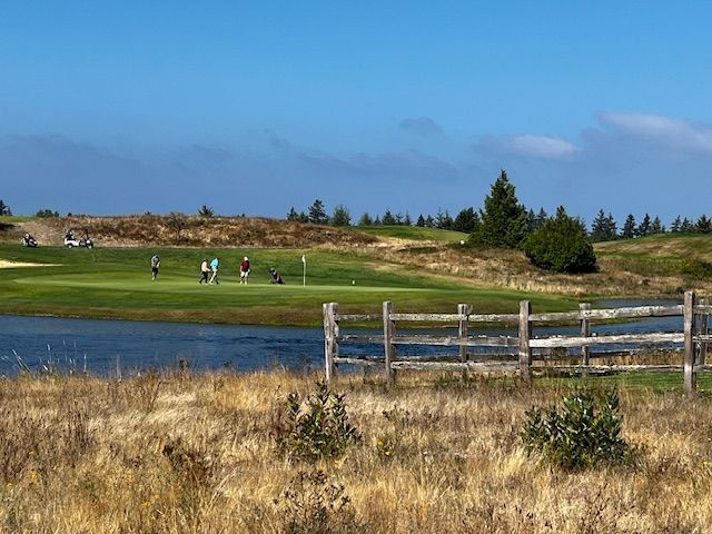 A group of people are playing golf on a golf course next to a lake.