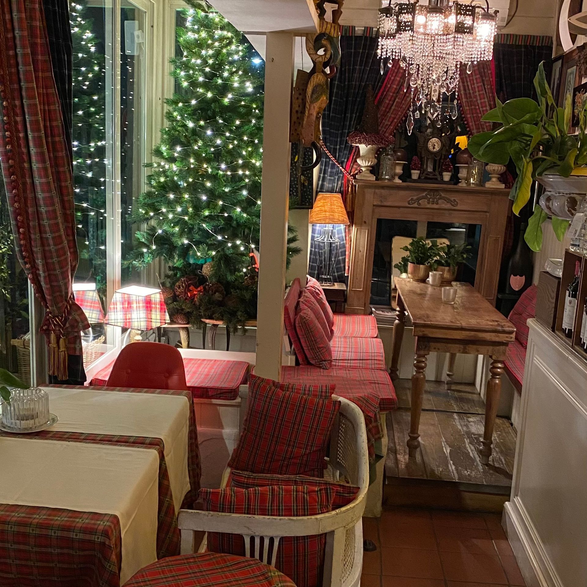 L'interno di un ristorante accogliente e illuminato da una luce calda, caratterizzato da festosi alberi di Natale, mobili rustici in legno e decorazioni a motivi geometrici.