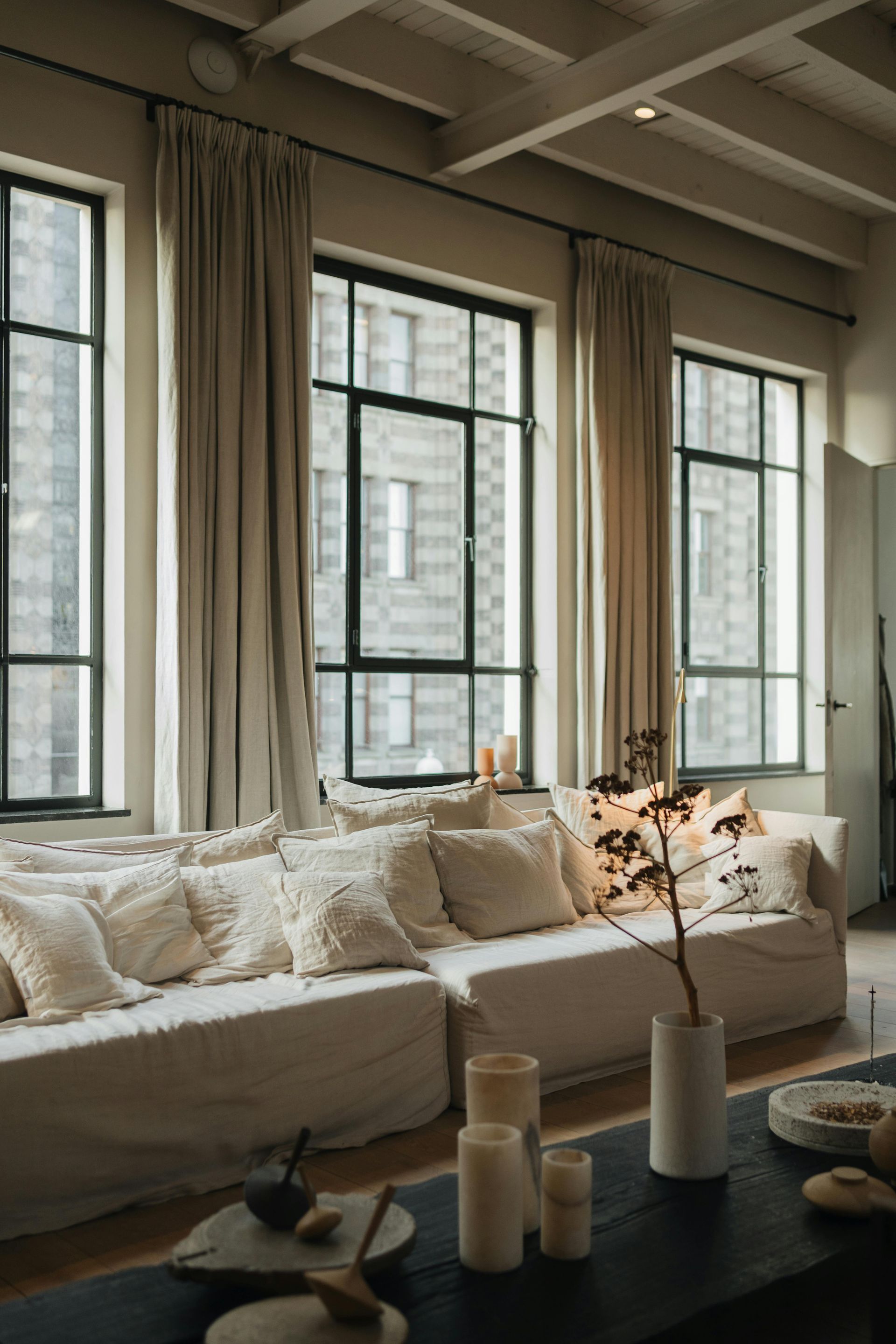 A living room with a couch , table , and windows.