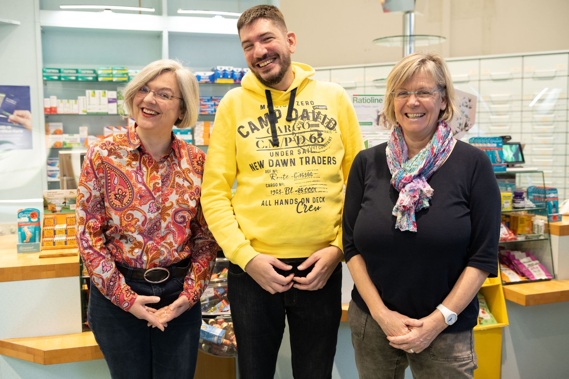 Eine Gruppe von Menschen posiert in einer Apotheke für ein Foto.