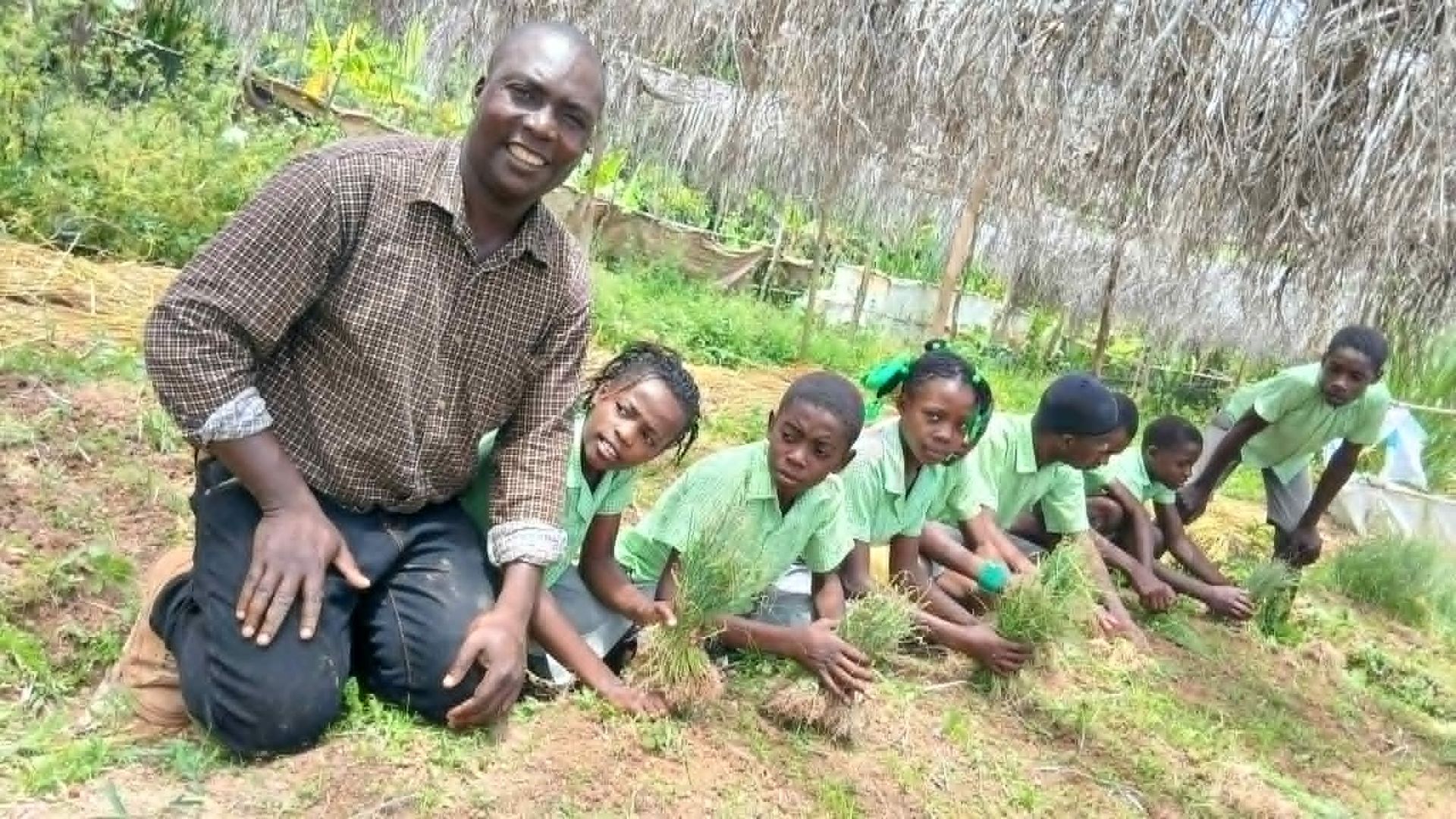 Samuel and students kneeling in a garden.