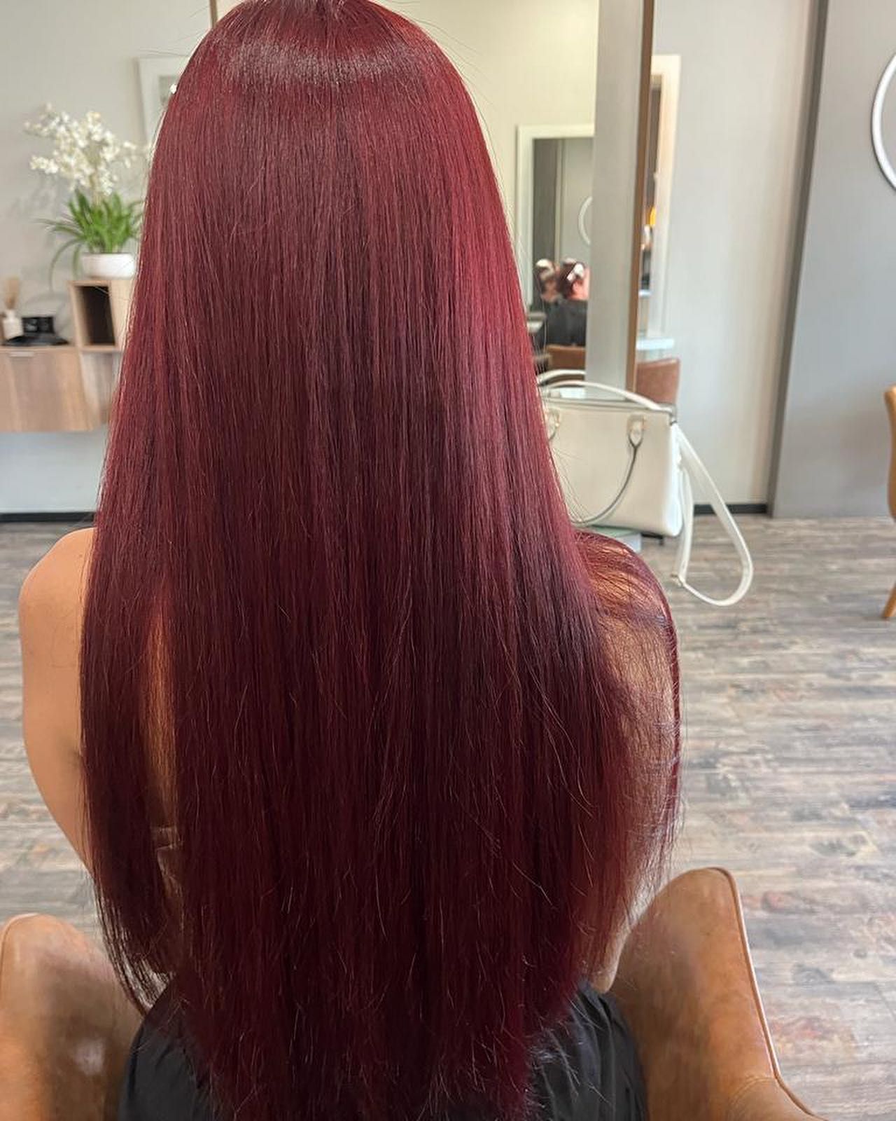 Person with Long Burgundy Straight Hair Seen from Behind in A Salon Chair — Carlee Hair Design In Anula, NT