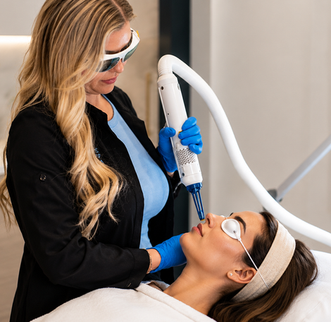 Aesthetic treatment provider using a handheld laser on a woman’s face in a clinic