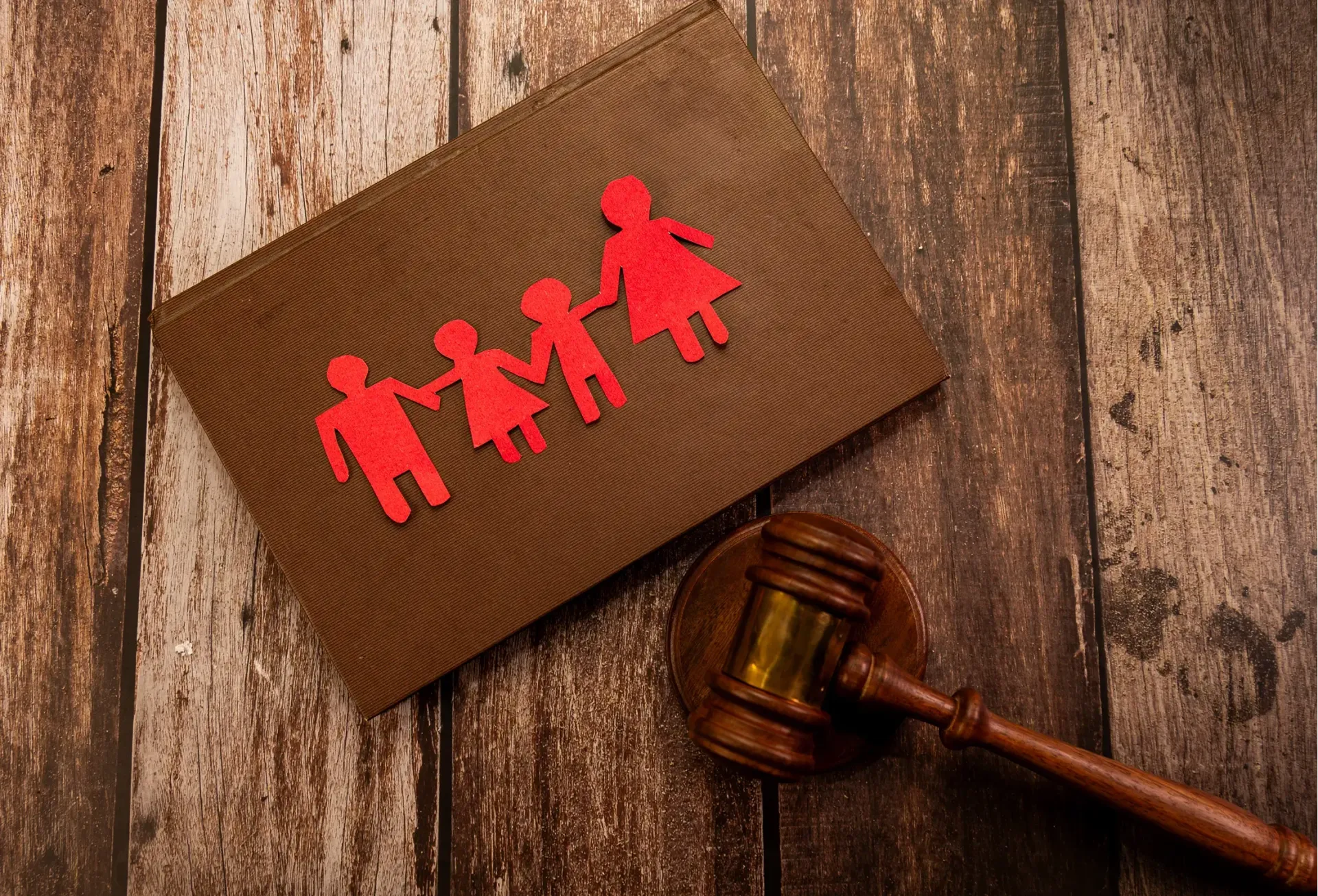A brown book on a table with paper design of a family, color red