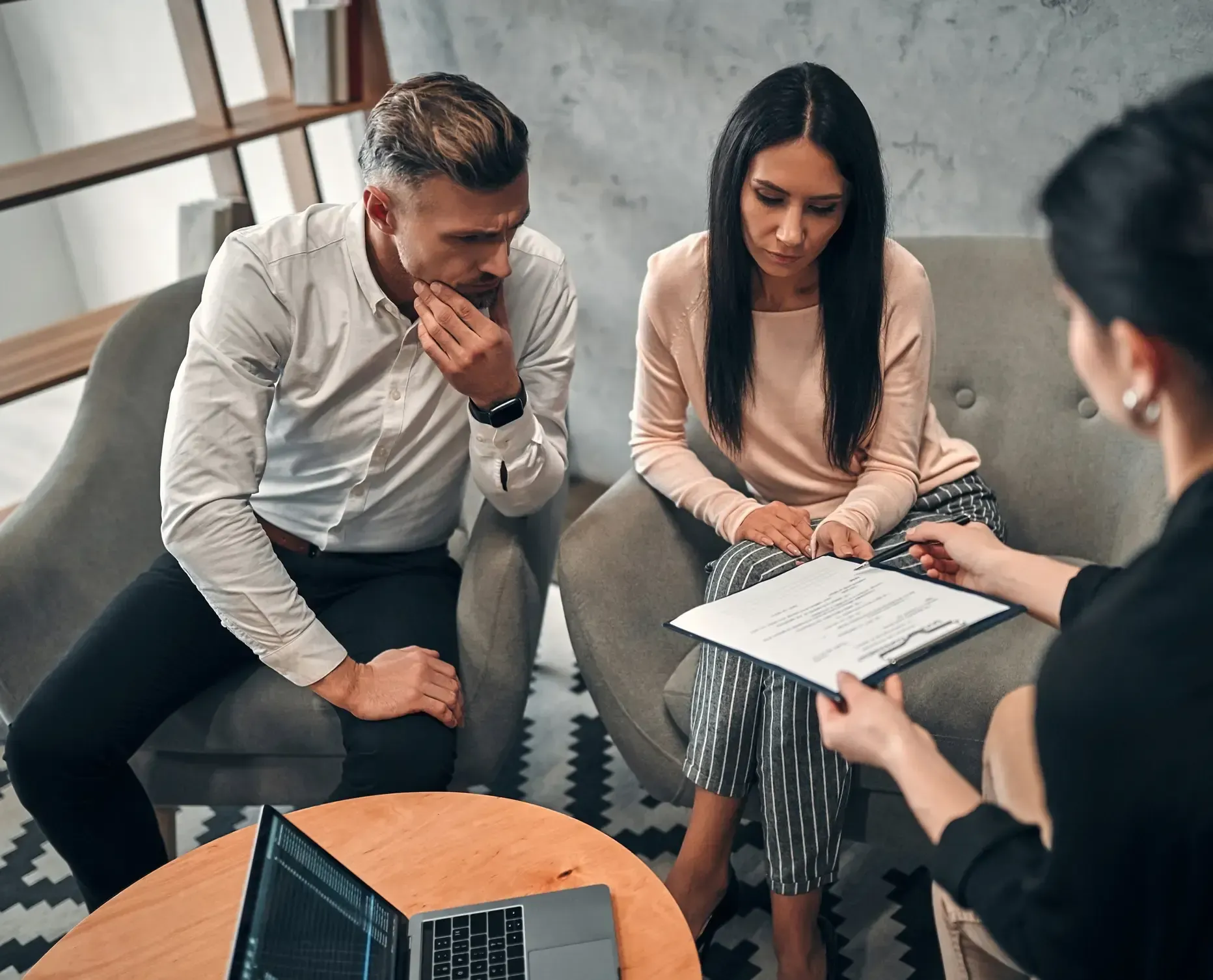 Three people discussing, one is holding a white paper with a writing on it.