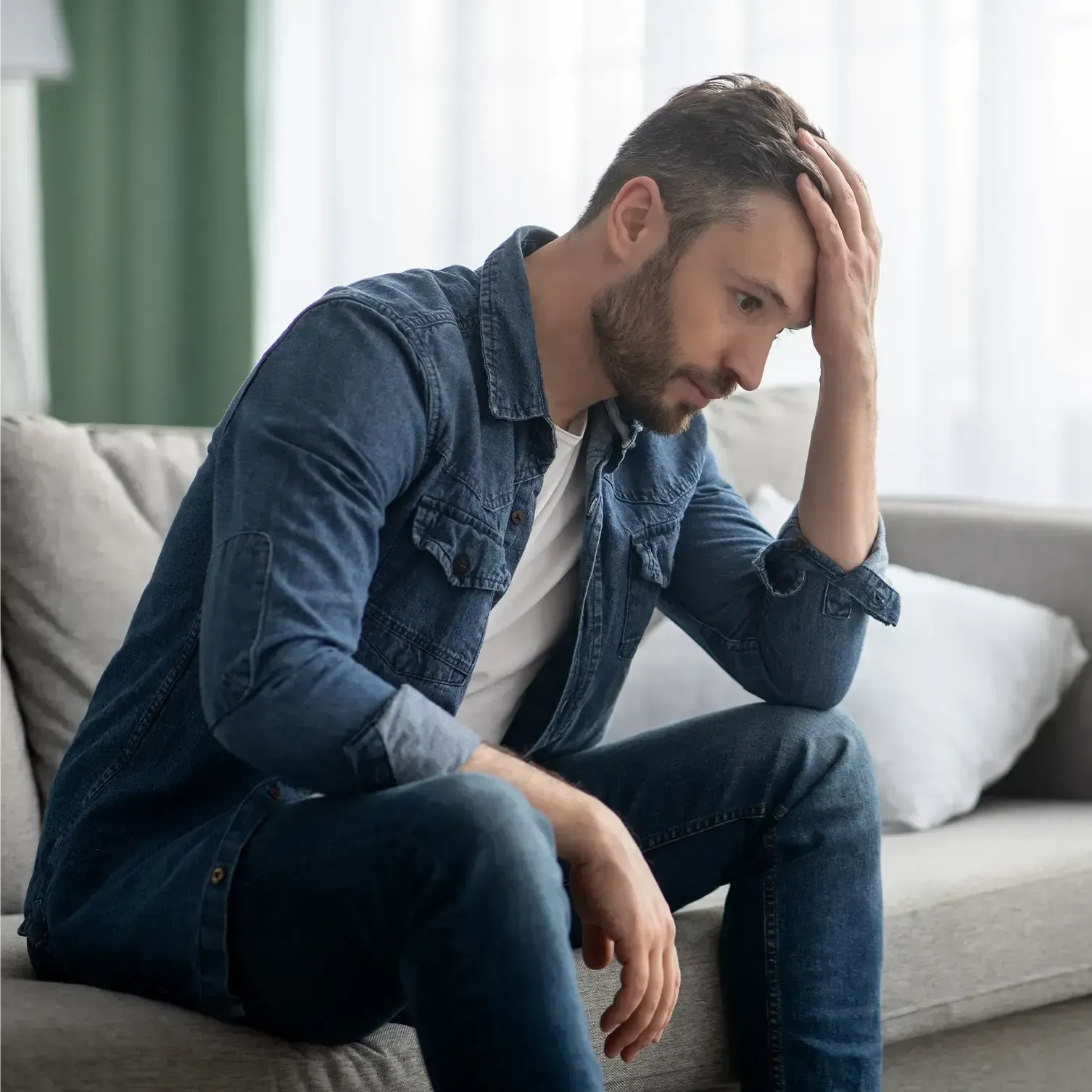 A distressed man holding his forehead